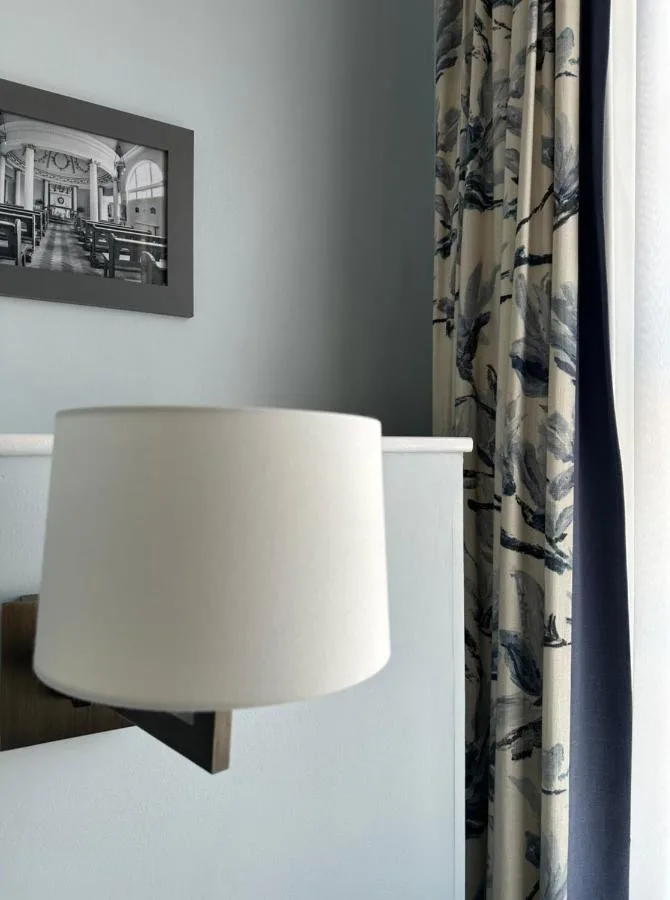 A white table with a lamp and curtain at The Bar Convent Guest House on Blossom Street, York