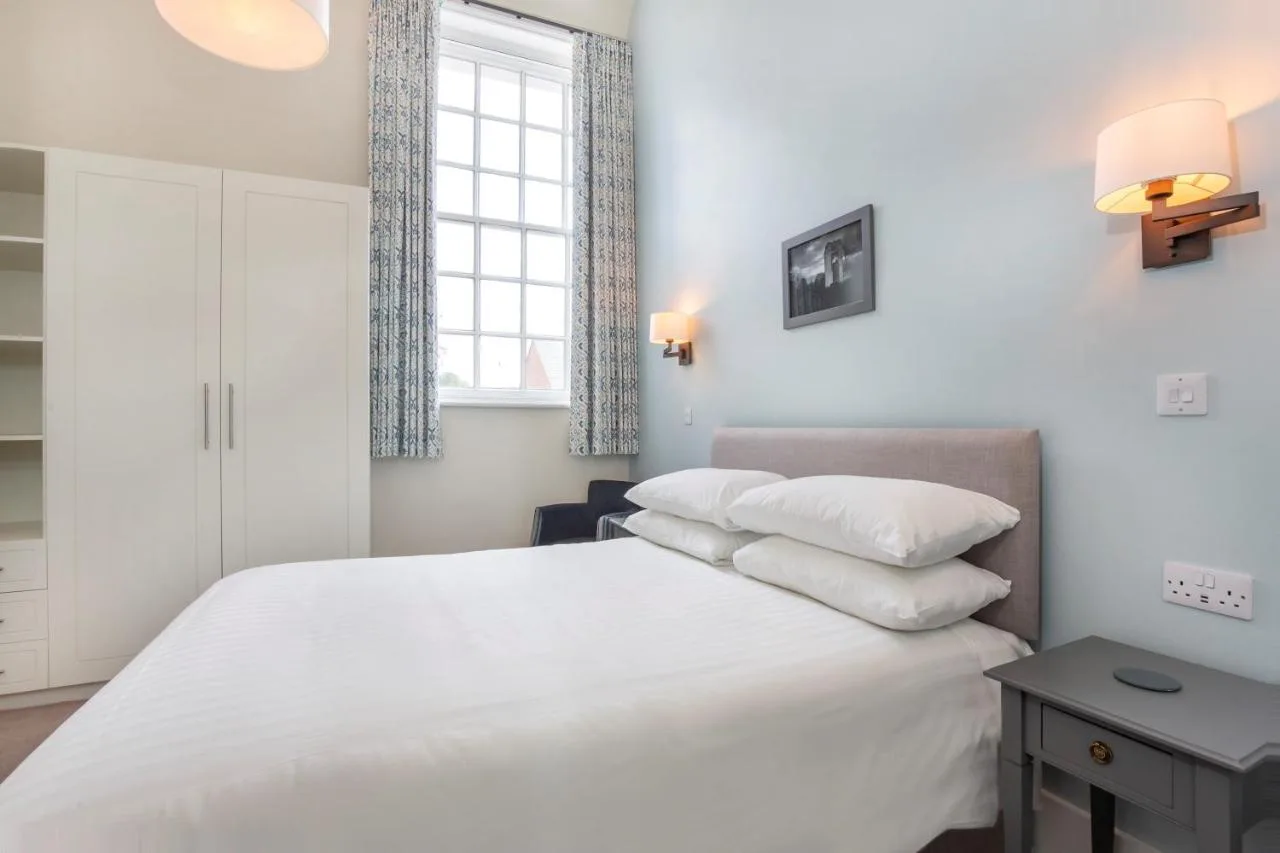 A bedroom with crisp white sheets and natural light at The Bar Convent Guest House