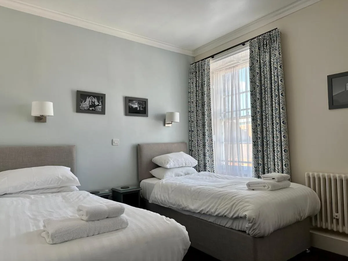 A twin hotel room with two beds and a window